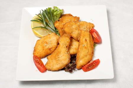 Fried turkey steak with tomatoes and lemonの写真素材