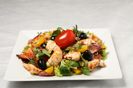 Chicken salad on the white plate with red tomatoの写真素材