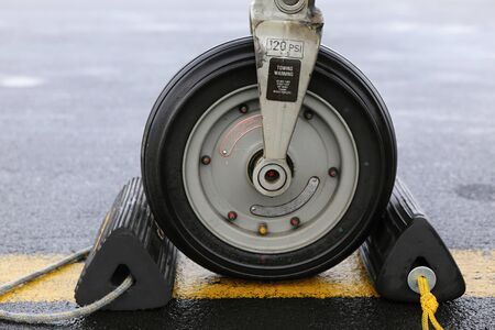 Front wheel of the aircraft with black parking blocksの写真素材