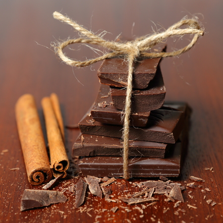 Stock of the chocolate with the cinnamon and the pieces on the brown deskの写真素材