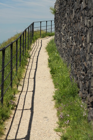 Path between the stony wall and metal railingの写真素材