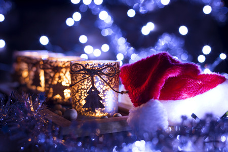 Advent, four candles Christmas decoration and next Santa Claus hat on a background of lightsの写真素材