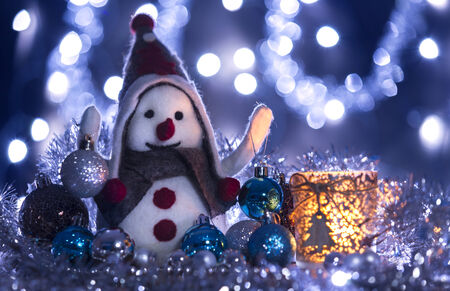 Snowman smiling brought Christmas balls, blue background with flashing lightsの写真素材