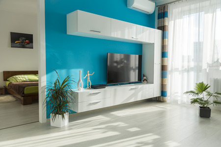 Modern sunny living room with TV and view into the bedroomの写真素材