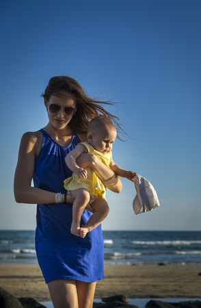 sexy mother walks with baby at seaの写真素材