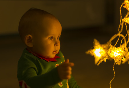 Santa helper baby on the floor decomposes Christmas lights that are shaped like stars