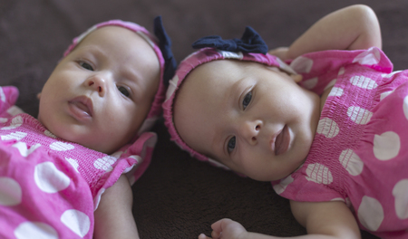 Cute twins babatka with headband with ribbon and pink dress with white polka dotsの写真素材