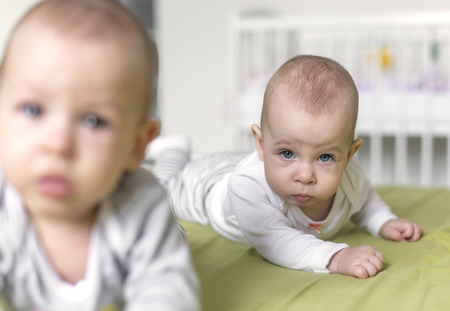 Cheerful twins on the bed. 6 months old