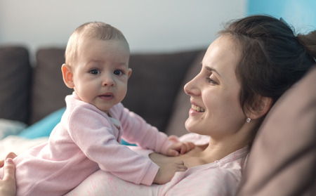 happy loving family. mother playing with her baby in the sofaの写真素材