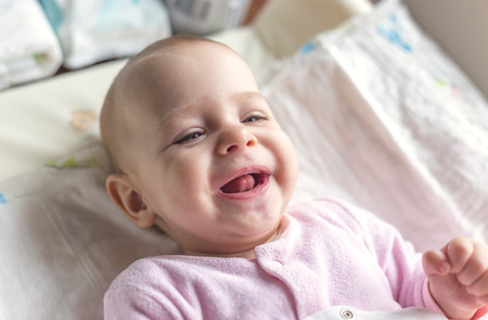 Portrait of a smiling baby laying on a changing table