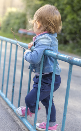 Sadly bored little girl in the park rest on railingの写真素材