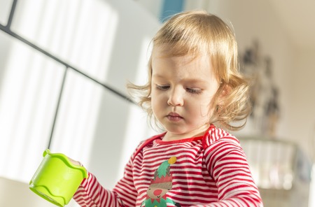 in a beautiful sunny apartment the cute child sits barefoot on the floor and plays. Closeupの写真素材