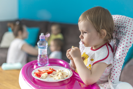 Baby breakfasts tomatoes with bread alone on highchairの写真素材