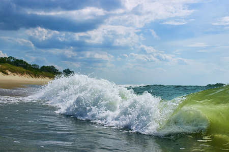 Sea surf splash of turquoise wave with a sandy beach and beautiful sky