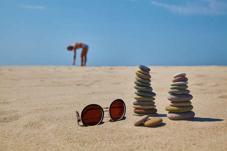 Cairn of stones and sunglasses on the sandy beachの写真素材
