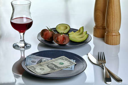 Plate with dollars and a plate of food on a white served table. Restaurant tip concept