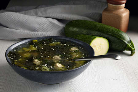 Zucchini soup with meatballs on a white table against the background of a gray kitchen towelの写真素材