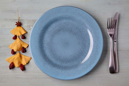 Empty blue plate with cutlery and a Christmas tree