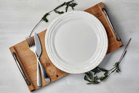 White ceramic plate and a tray with cutlery and dry currant sprigsの写真素材