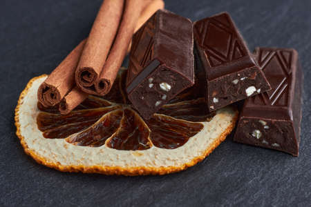 Dark chocolate bars with chopped almonds, dried orange wedgesの写真素材