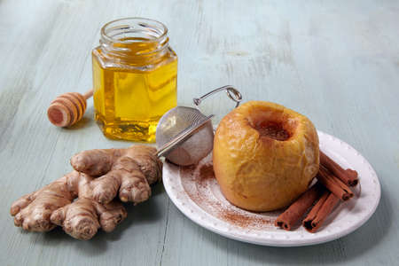 Baked apple with honey, cinnamon and ginger on a light wooden tableの写真素材
