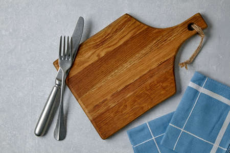 Brown wooden cutting board with cutlery and dinner napkins