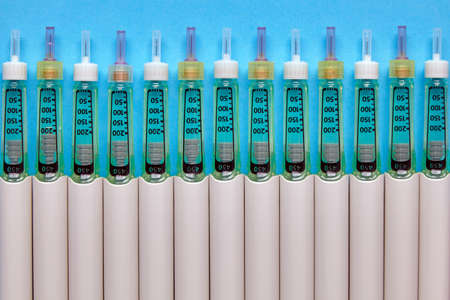 Syringe pens with insulin lined up in a row on a blue background. Top view with copy space. flat layの写真素材