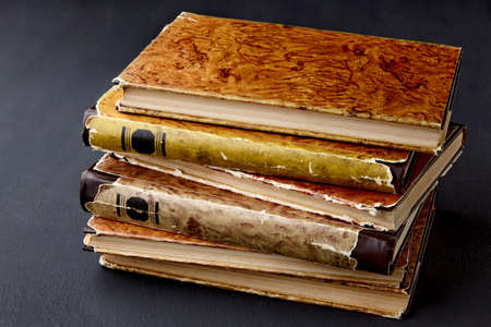 A stack of vintage dilapidated books on a dark concrete table. library night