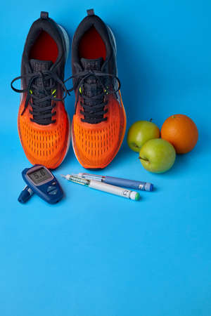 Orange sneakers, green apples, oranges, glucometer and insulin syringe pensの写真素材