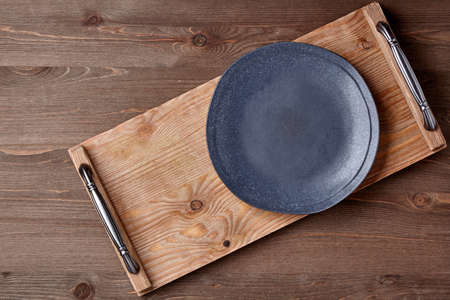 White ceramic plate and brown wooden tray on a grunge wooden table. Layout for display dishes. top...