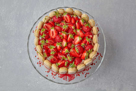 Dessert with strawberries, savoiardi cookies and mascarpone tied with a red ribbon on a light concrete table. Top view with copy space. flat layの写真素材