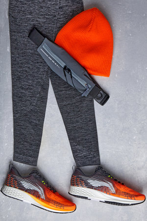 An orange knitted warm hat, warm sports leggings, a fanny pack with headphones and orange sneakers...