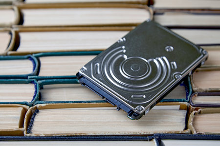Computer hard drive on the background of a stack of old paper books
