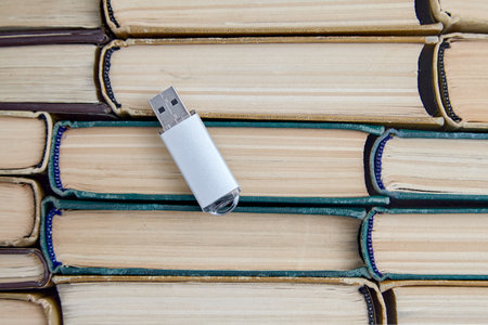 USB flash drive of a computer on the background of a stack of old paper booksの写真素材