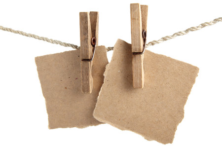 Craft note paper pinned with a vintage clothespin on a rope on a white backgroundの写真素材
