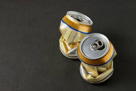 Flattened aluminum cans of beer on a black kitchen tableの写真素材