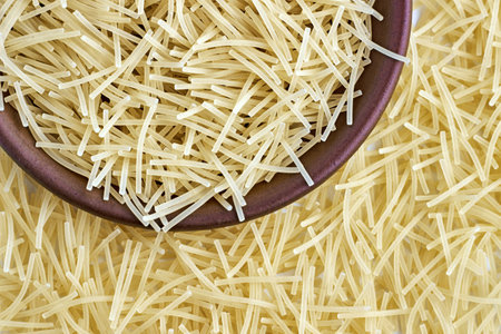 Egg noodles, pasta, in a brown ceramic bowl and scattered around isolated on white background. top view with copy spaceの写真素材