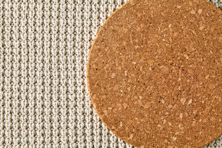 cork stand against a background of rough beige knitted clothes. background for food display. top view with copy spaceの写真素材