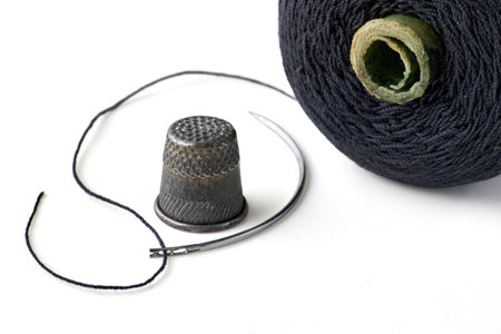 Semicircular needle with black thread and spool and vintage old thimble isolated on white...