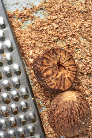 Nutmeg and metal grater against nutmeg powder on blue background.の写真素材