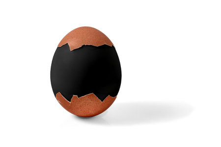 Half shelled boiled Easter chicken egg painted in black mourning color isolated on a white background.の写真素材