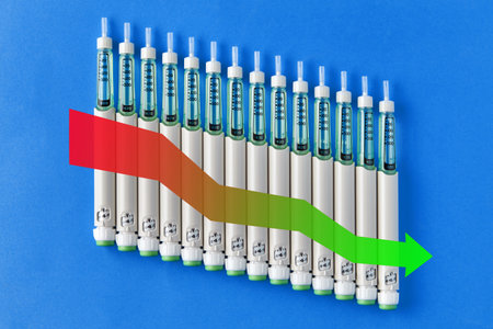 Row of insulin pens with arrow pointing down. Reduction in drug prices or reduction in drug...