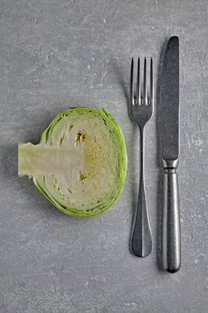 cabbage cross section and cutlery fork and knife on a gray stone table. healthy dietary concept. top viewの写真素材