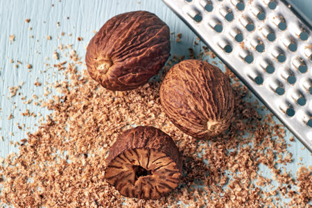 nutmegs grated on a metal grater on a blue wooden painted table.の写真素材