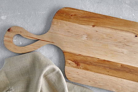 Empty wooden cutting board and linen napkin on stone grey surface