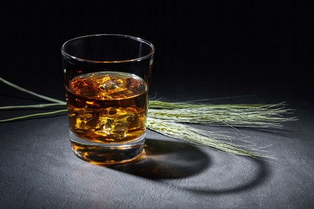 glass of amber whiskey on a black stone table.