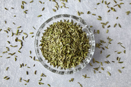 Fennel in a crystal bowl scattered on a gray concrete table, top view.の写真素材