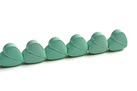Turquoise heart-shaped pills lined up on a white background.