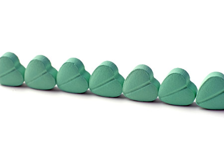 Sweet turquoise mint tablets in the shape of a heart, lined up on a white background
