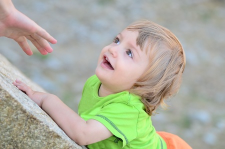 mother reaches out her baby on a rockの写真素材